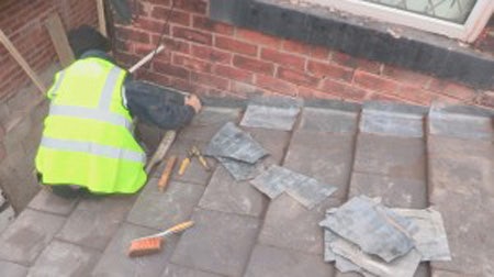 A workman installs lead flashing where the roof and wall meet, this stops water entering the bricks or roof edge.