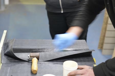 Applying primer with a scourer with the sheet held back by a roller
