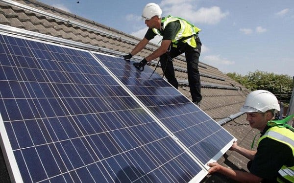 Workmen installing solar panels on a UK roof.