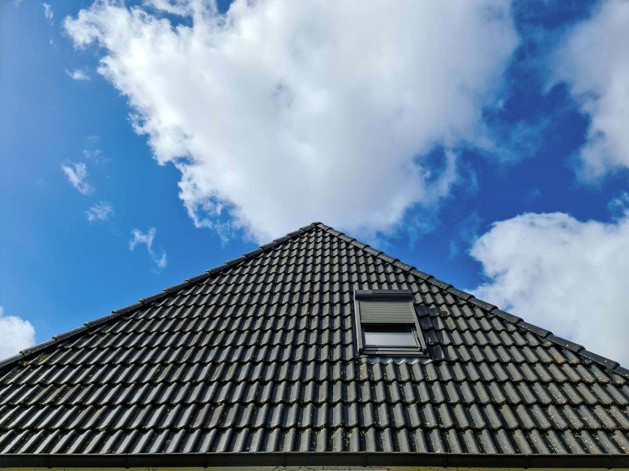 Open roof window in velux style with black roof tiles