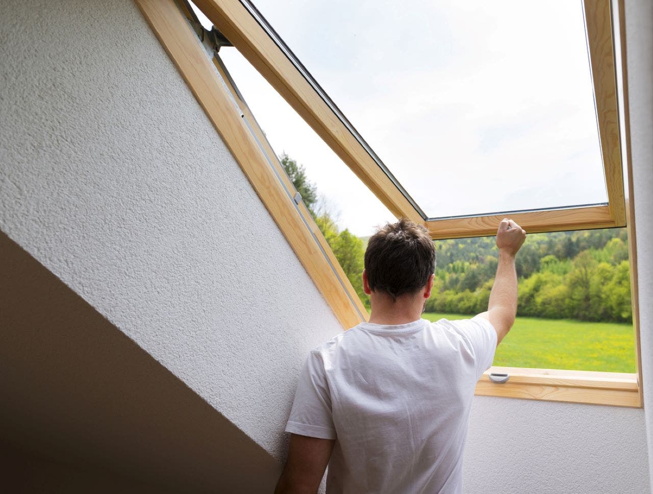 man checking his roof window for leaks
