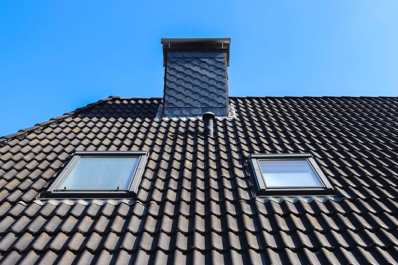 Roof window in velux style with black roof tiles